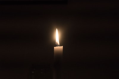 Lightened taper candle in the dark surroundings