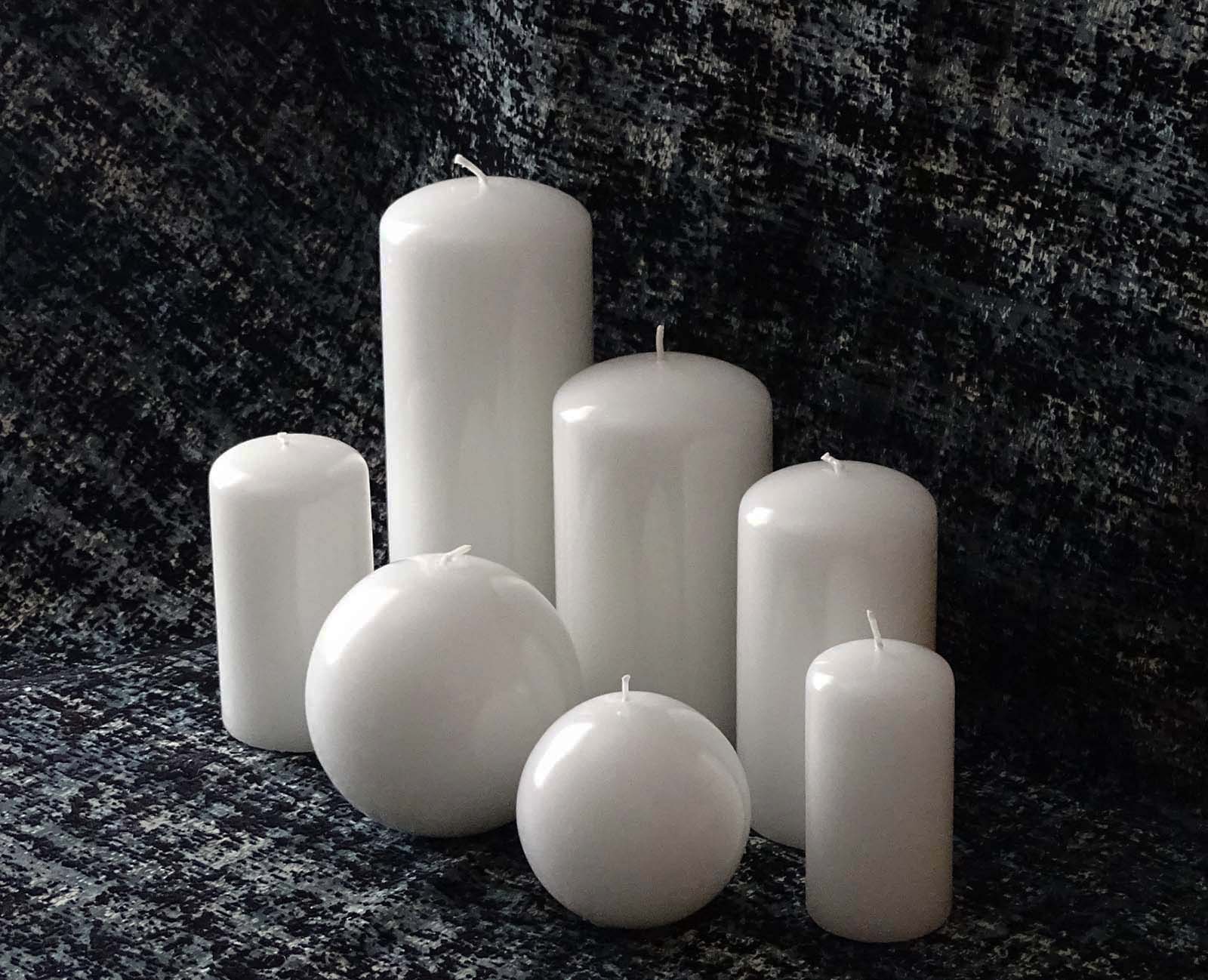 Set of five pillar and two round white candles on the black and gray table cloth